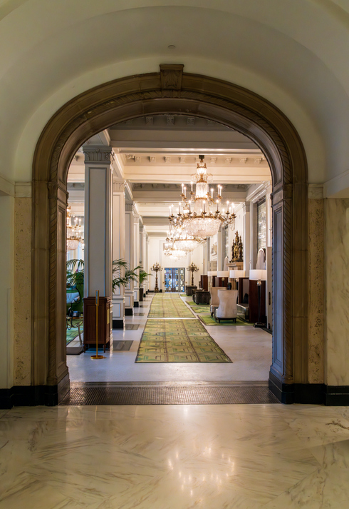 An elegant hallway at the St. Anthony Hotel featuring ornate chandeliers and classic architecture