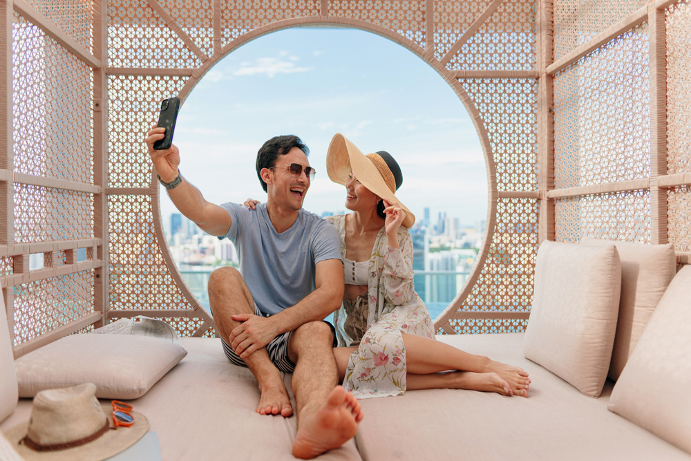 Beautiful Asian traveling couple taking selfie photos by the hotel poolside