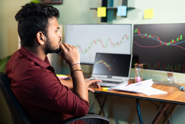 Side view of Trader analyzing share market by looking charts in multiple monitors or making strategy at home office - concept of studying equity market, waiting for success.